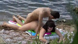 Couple climbing on the nudist beach